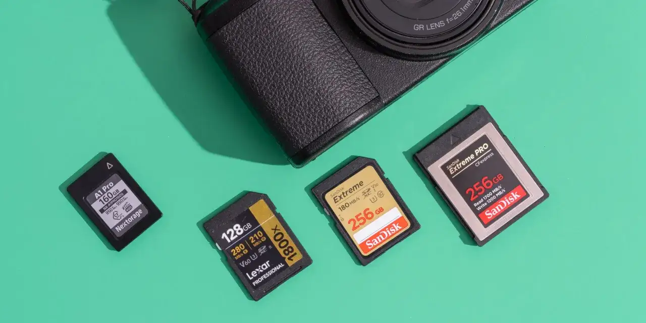 Karta flash SanDisk Extreme PRO 256 GB obok innych kart pamięci i fragmentu aparatu.