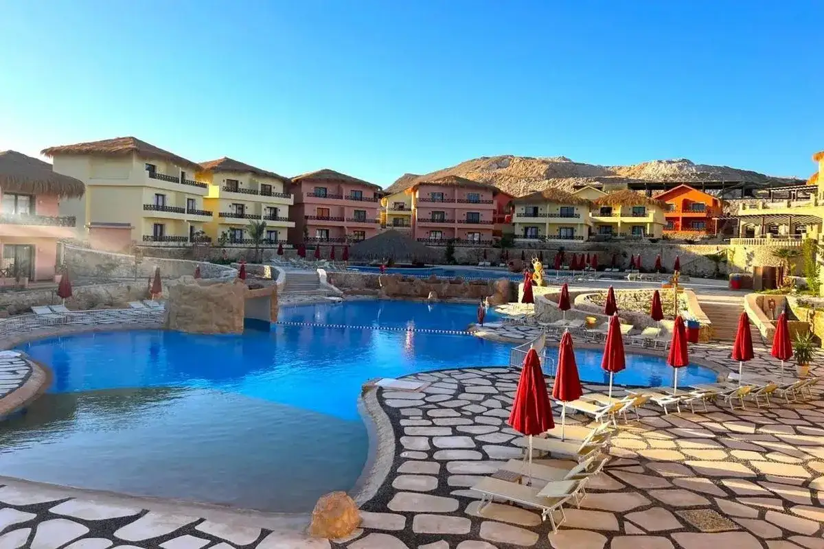 Idealne miejsce, by zapytać, gdzie na all inclusive w maju. Resort z basenami, kolorowymi budynkami i górami w tle.