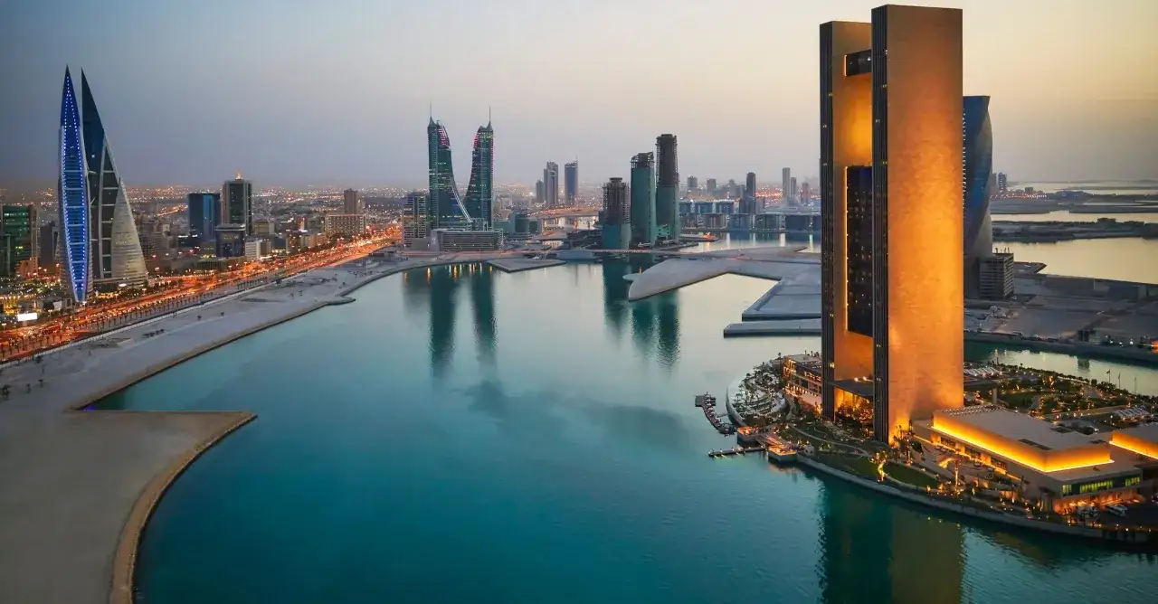 Moderne Skyline am Bahrain Port bei Dämmerung. Türme spiegeln sich im ruhigen Wasser.