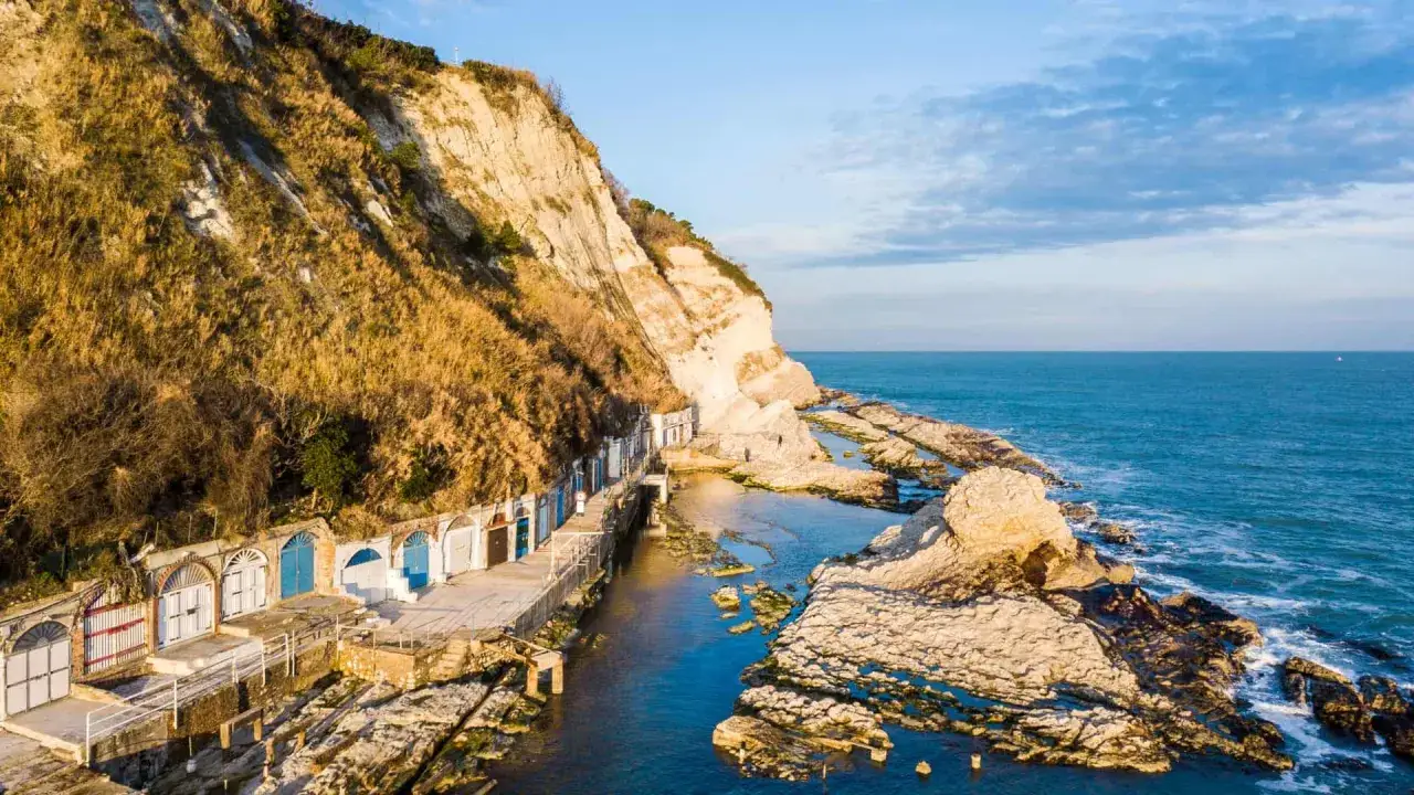 Le grotte marine e le casette dei pescatori, un angolo suggestivo da scoprire tra le cose da vedere ad Ancona, con il mare Adriatico sullo sfondo.
