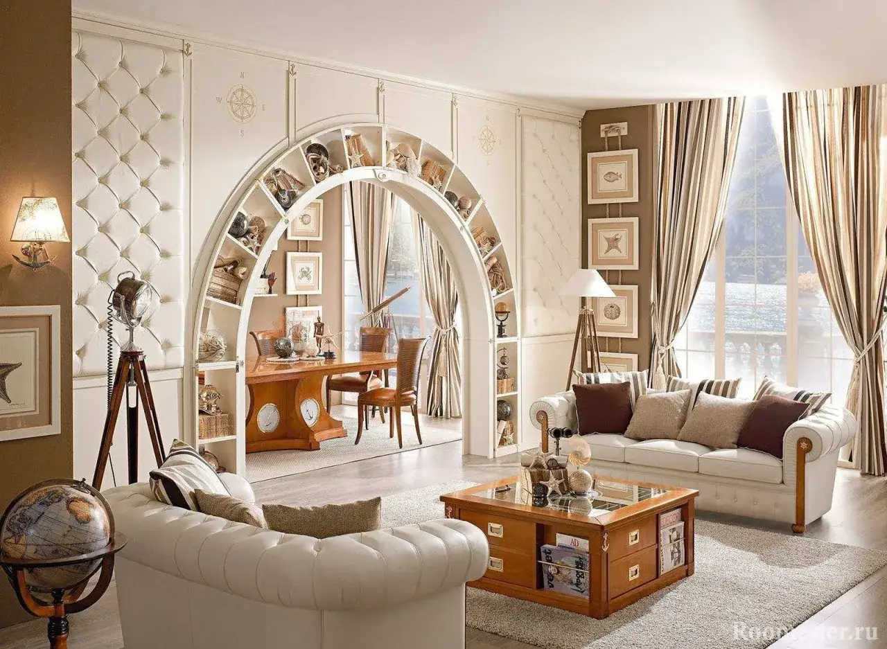 Un &eacute;l&eacute;gant salon avec un habillage arche maison, des &eacute;tag&egrave;res remplies d'objets marins, un bureau et une vue sur la mer.