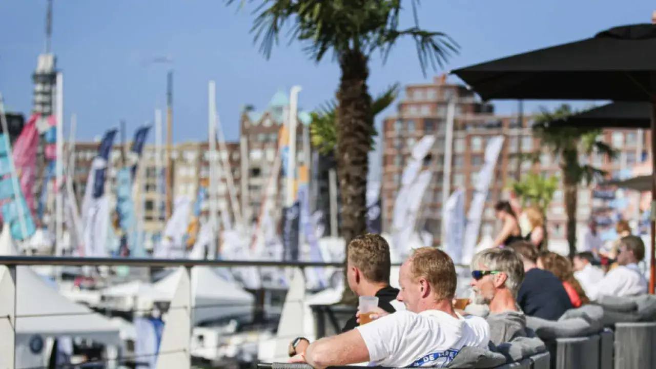 Genießen Sie die HISWA te water mit einem Drink in der Hand, während Boote und Palmen im Hintergrund vorbeiziehen.