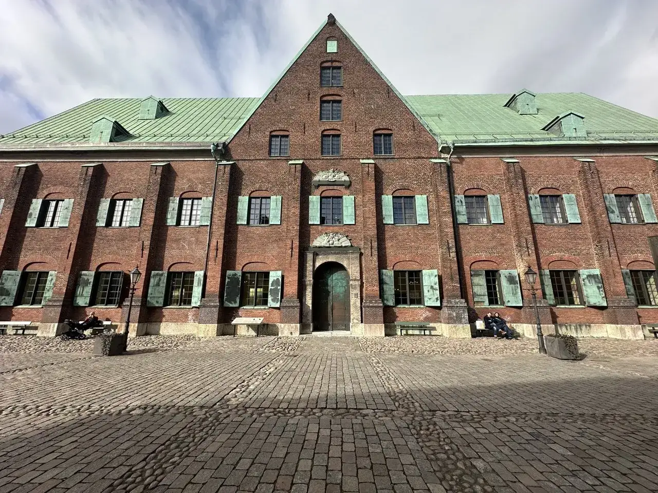 En vacker tegelbyggnad med grönt tak, kanske med ett mysigt cafe kronhuset.