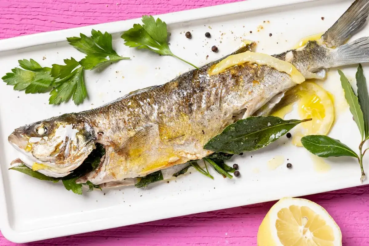 Branzino dorato e succulento, cotto alla perfezione nella friggitrice ad aria, guarnito con limone, erbe aromatiche e pepe nero.