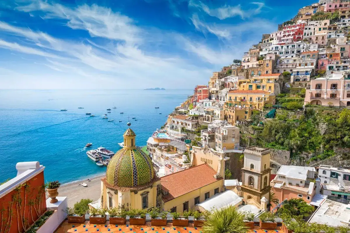Positano, uno dei paesi pi&ugrave; belli della costiera amalfitana, con case colorate a picco sul mare blu e barche all'ancora.