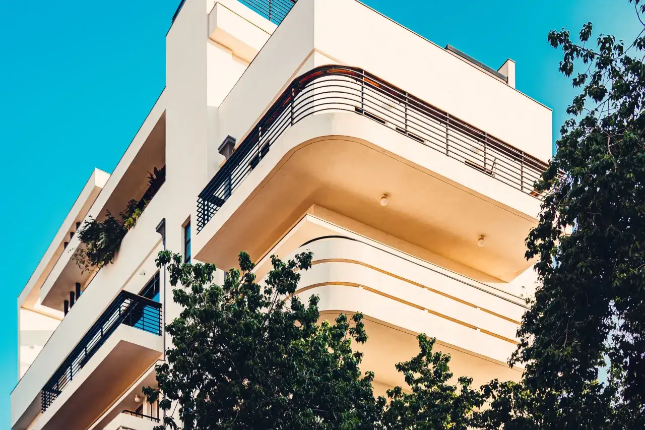 Curved balconies and clean lines define these Bauhaus architecture examples, set against a bright blue sky and lush green trees.