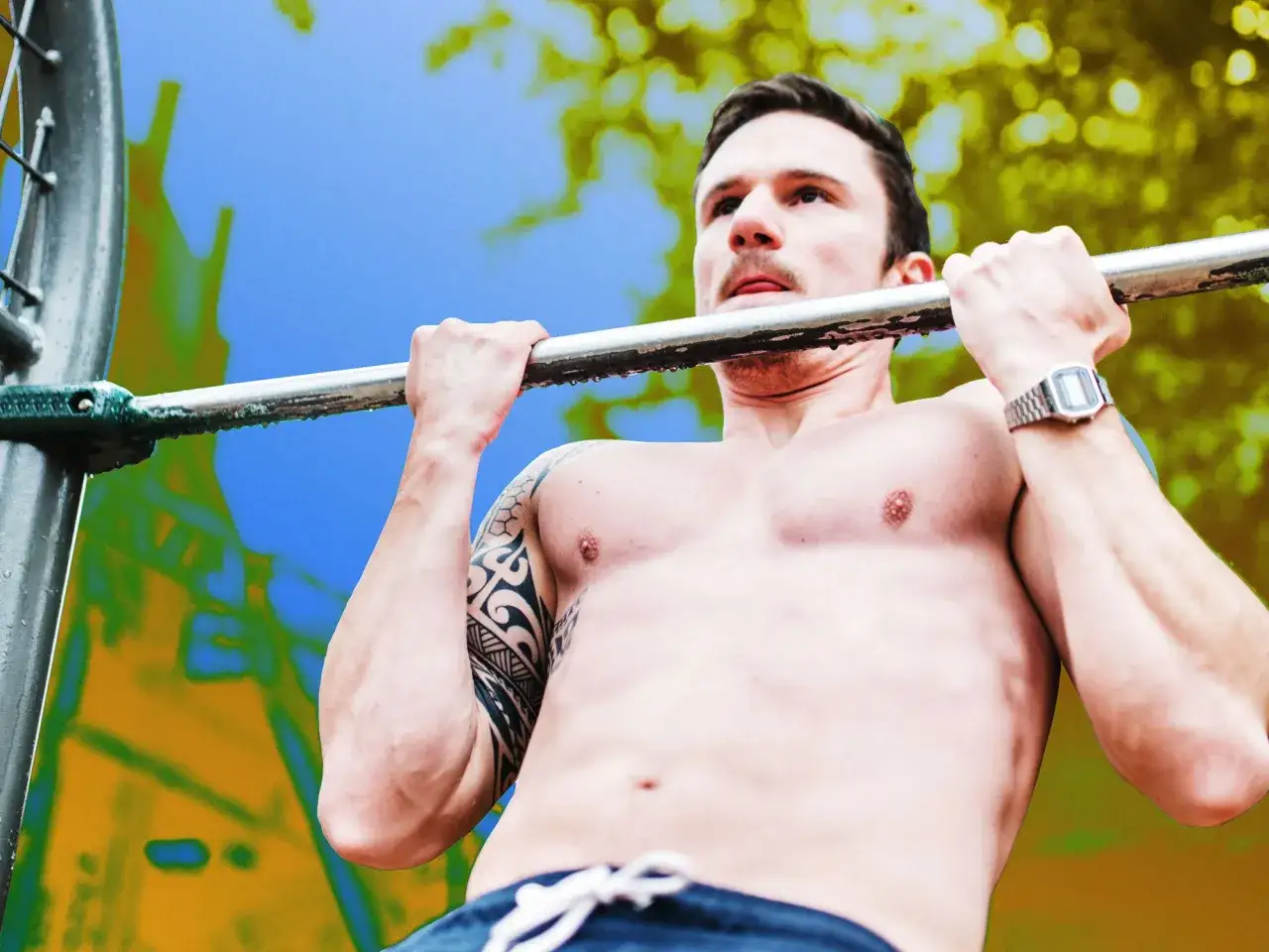 Man med tatueringar gör chin ups utomhus.