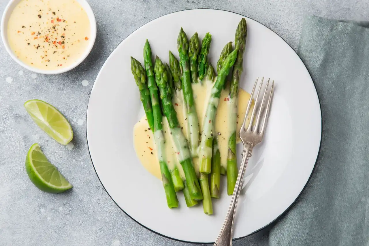 Frischer Spargel mit cremiger Sauce, garniert mit Pfeffer und Kräutern. Dazu passen Limettenspalten und weitere leckere Saucen zu Spargel.
