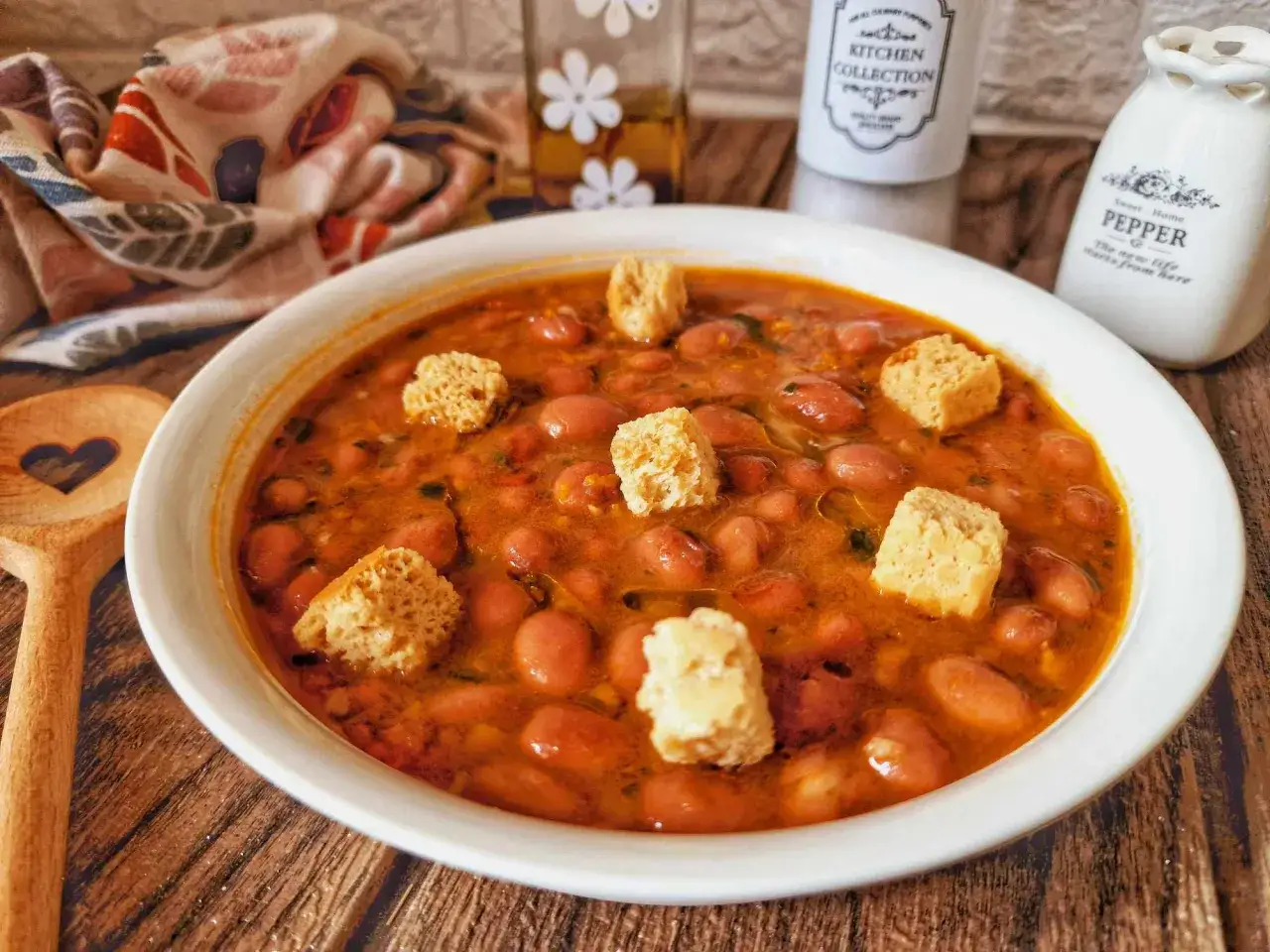 Una ciotola di zuppa di fagioli fumante, guarnita con crostini croccanti, pronta per essere gustata.
