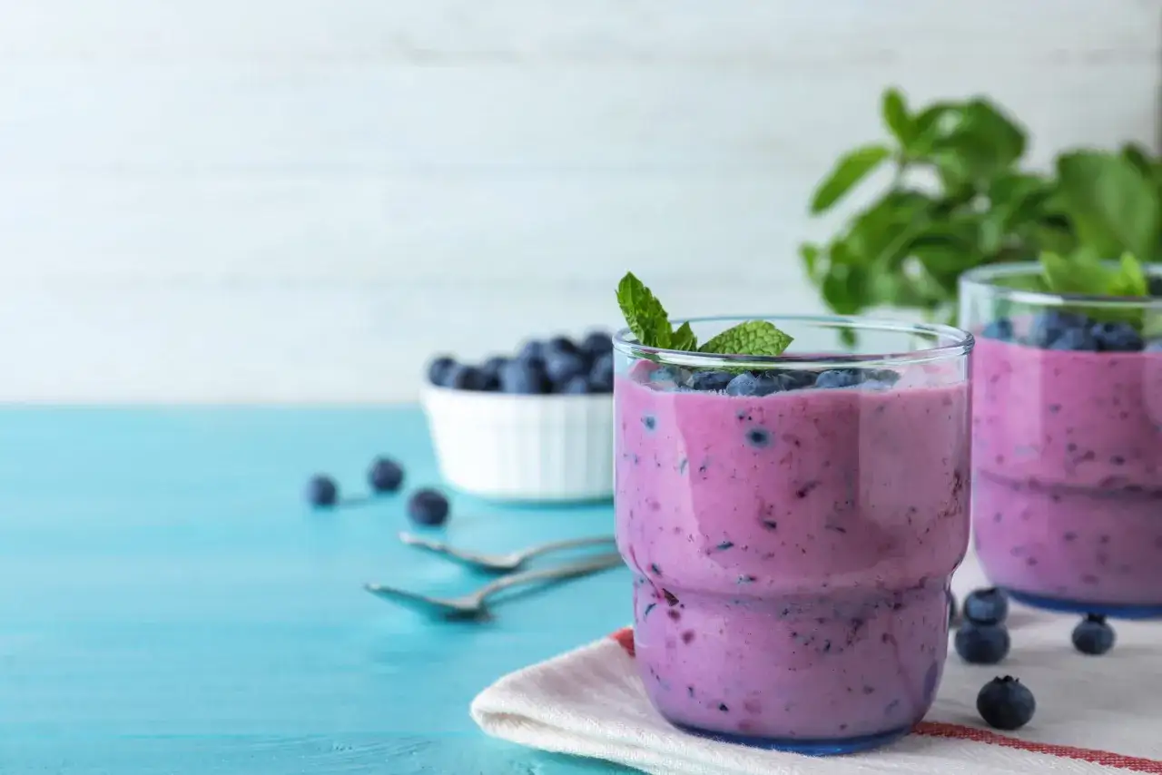 Świeży shake borówkowy w szklance z borówkami i miętą