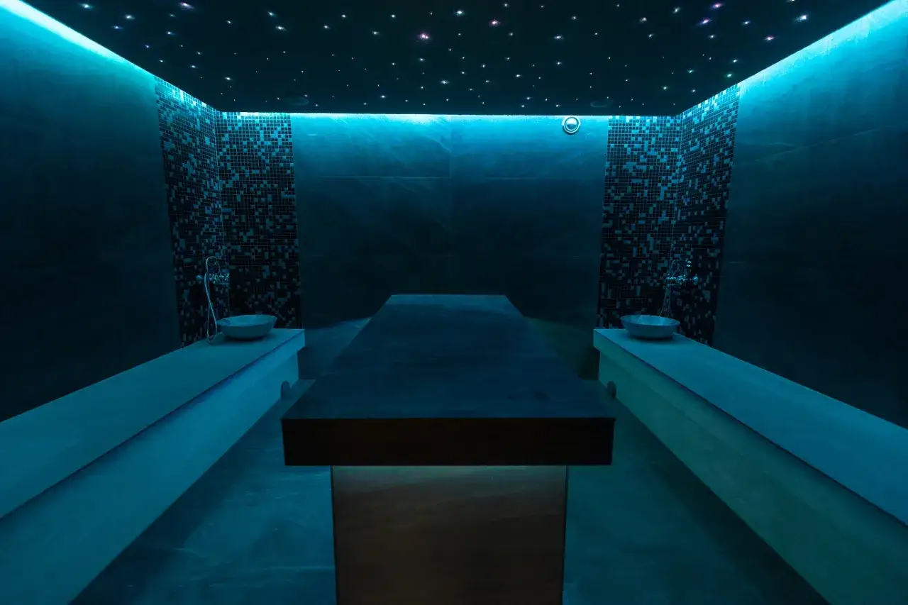 Relaks w hotelu premium Wisła: nowoczesne spa z prysznicami, kamiennymi ławami i stołem do masażu pod rozgwieżdżonym niebem.