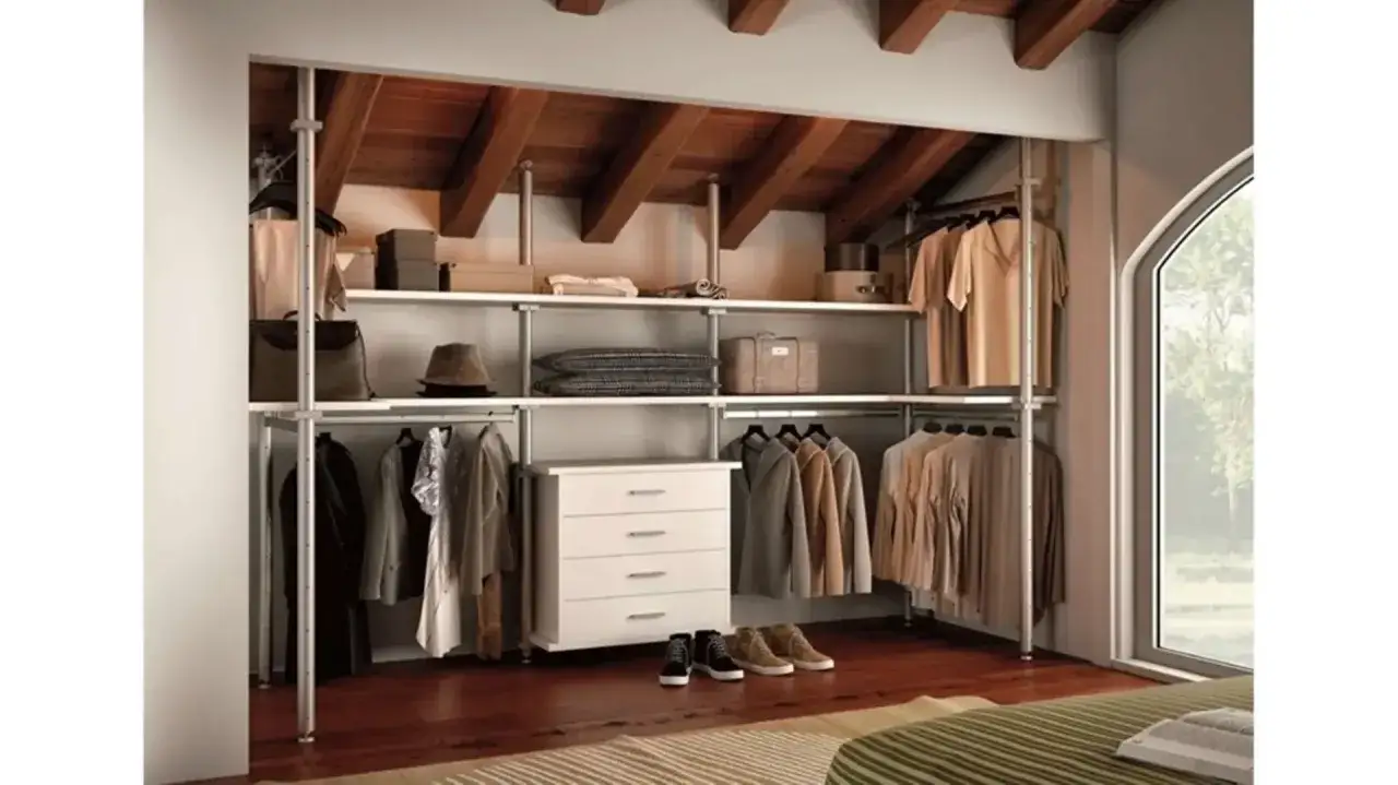 Cabina armadio mansarda bassa con scaffali e cassettiera, abiti appesi e accessori.