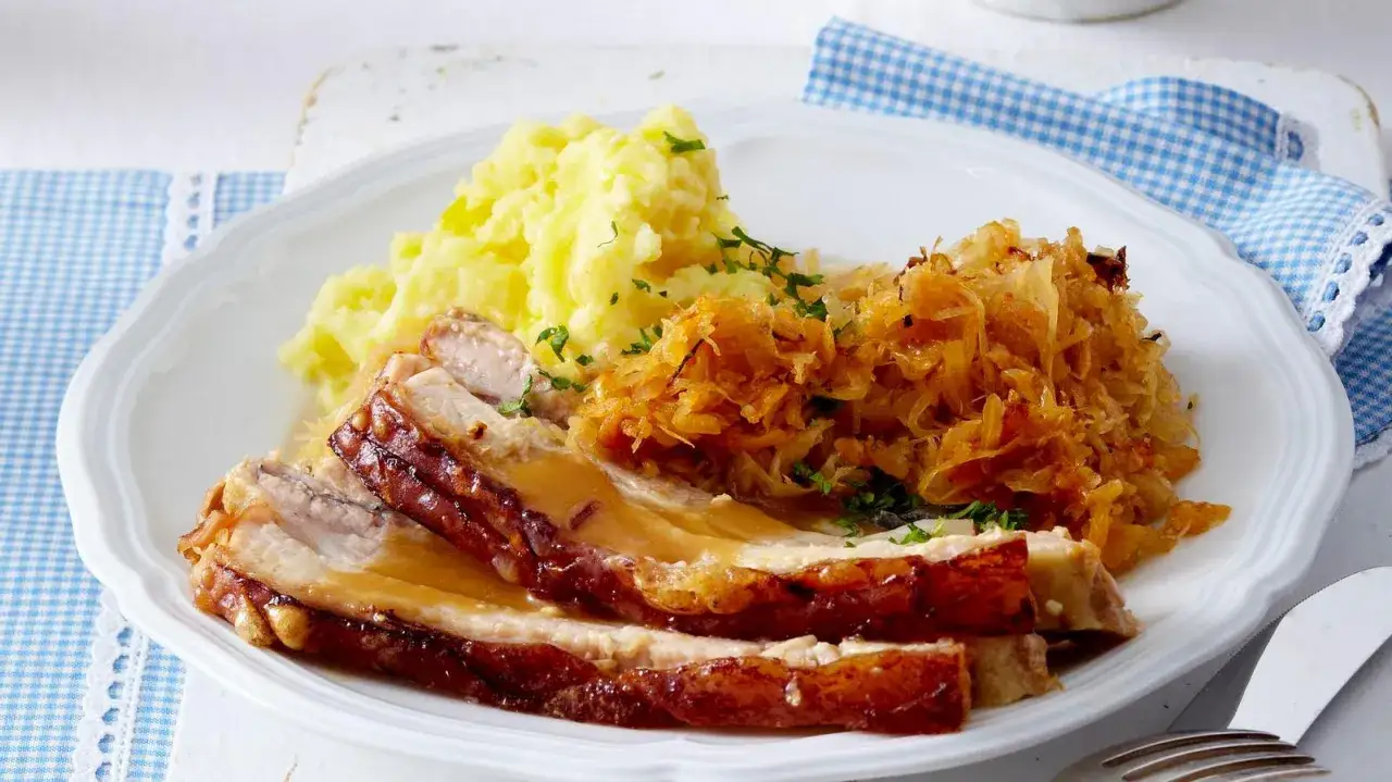 Schmackhaftes Schweinefleisch in Sauerkraut gekocht, serviert mit Kartoffelpüree und Petersilie.