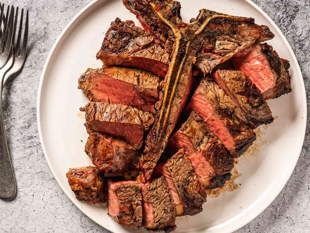 Perfekt gegrilltes T-Bone-Steak, in Scheiben geschnitten, zeigt die ideale Kerntemperatur f&uuml;r saftiges Fleisch.