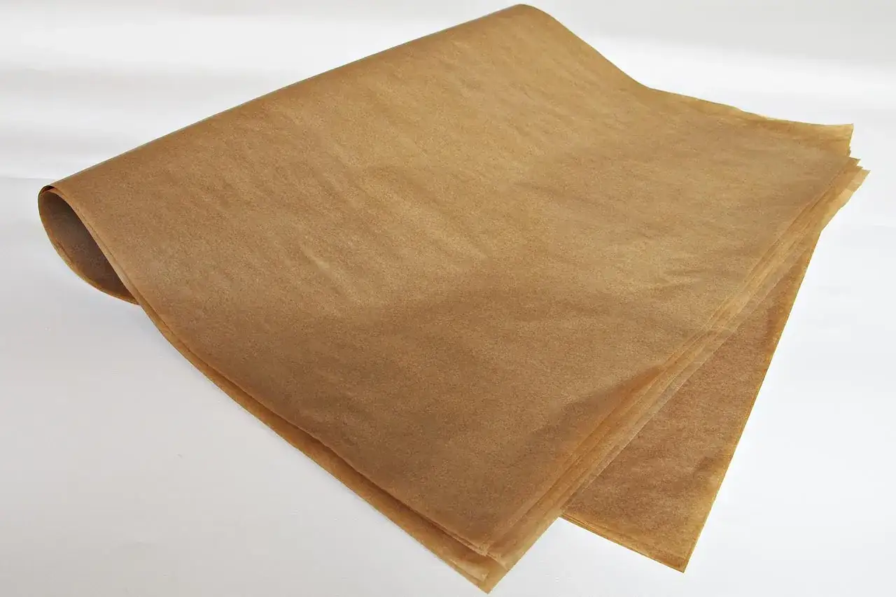 Kilka arkuszy papieru typu kraft, lekko pofałdowanych, tworzy naturalną, brązową stertę.
