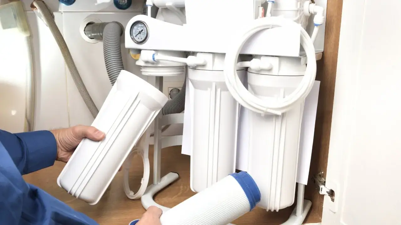 Wymiana filtra wody w domu: ręce trzymają nowe wkłady do systemu odwr&oacute;conej osmozy. Pamiętaj, co ile wymieniać filtr wody w domu.