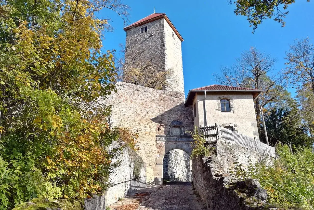 Herbstliche Bäume umgeben die imposante ruine lichtenburg mit ihrem steinernen Torbogen und dem hohen Turm.
