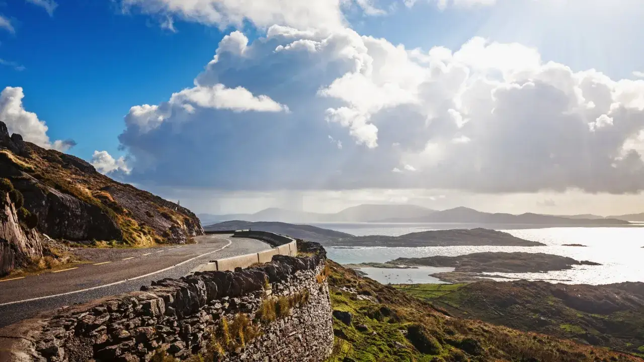 Scenic road winding along a rocky coast with a bay and islands, reminiscent of a Ring of Kerry map.