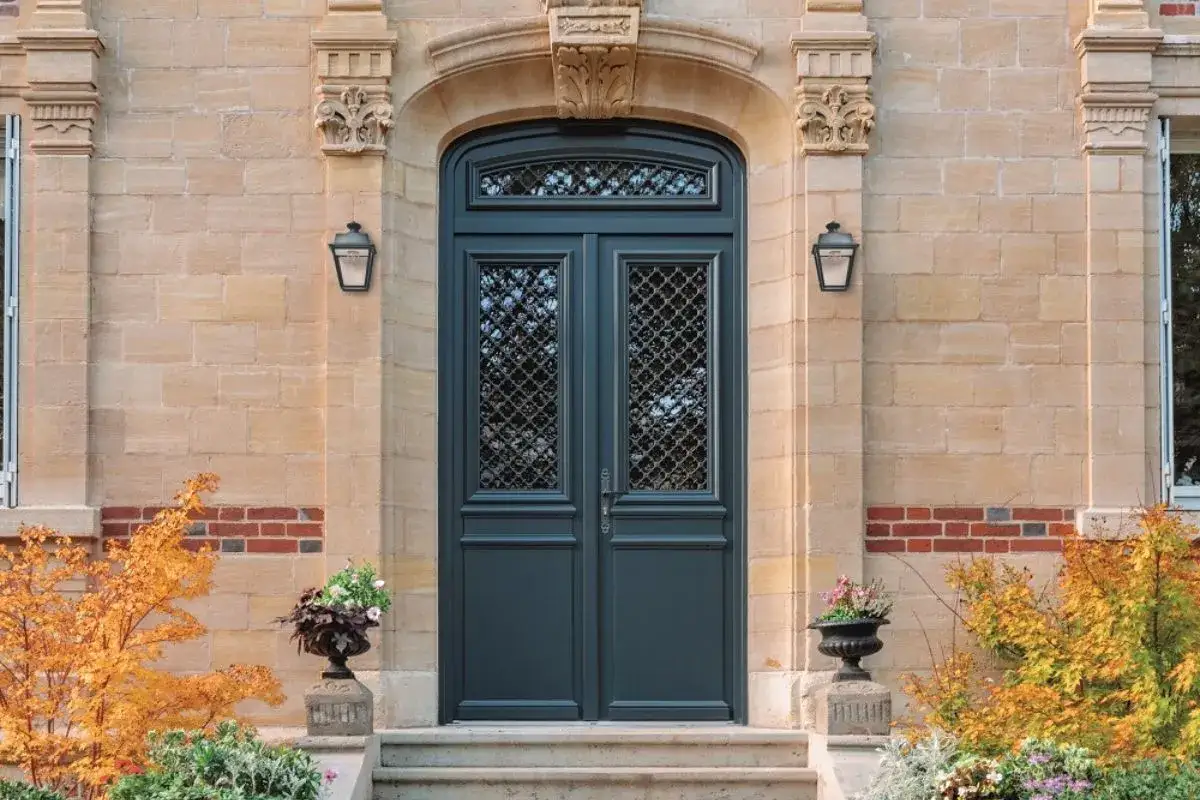 Une &eacute;l&eacute;gante porte synonyme de raffinement, avec ses vitraux grillag&eacute;s et ses lanternes classiques.