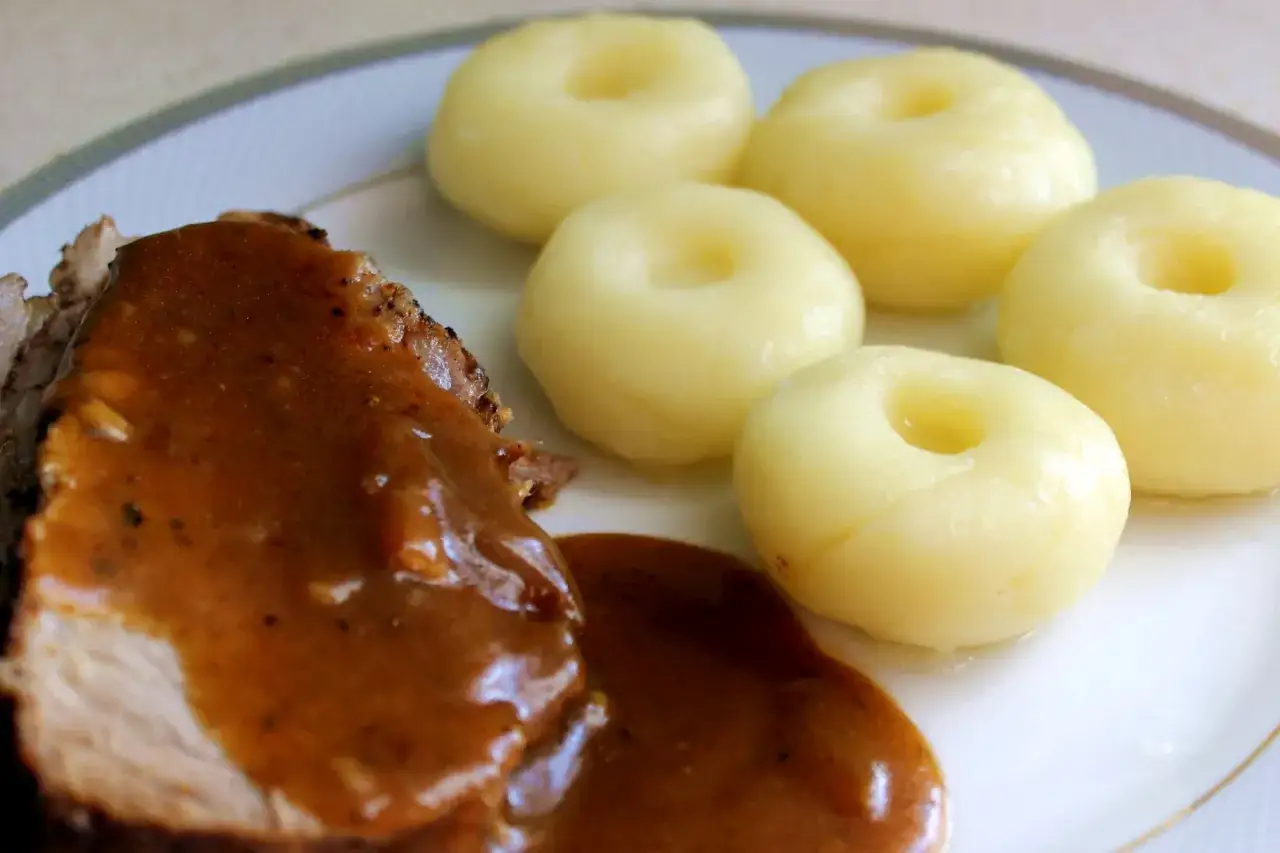 Karkówka w sosie pieczeniowym ciemnym, podana z kluskami śląskimi. Pyszny, tradycyjny obiad.