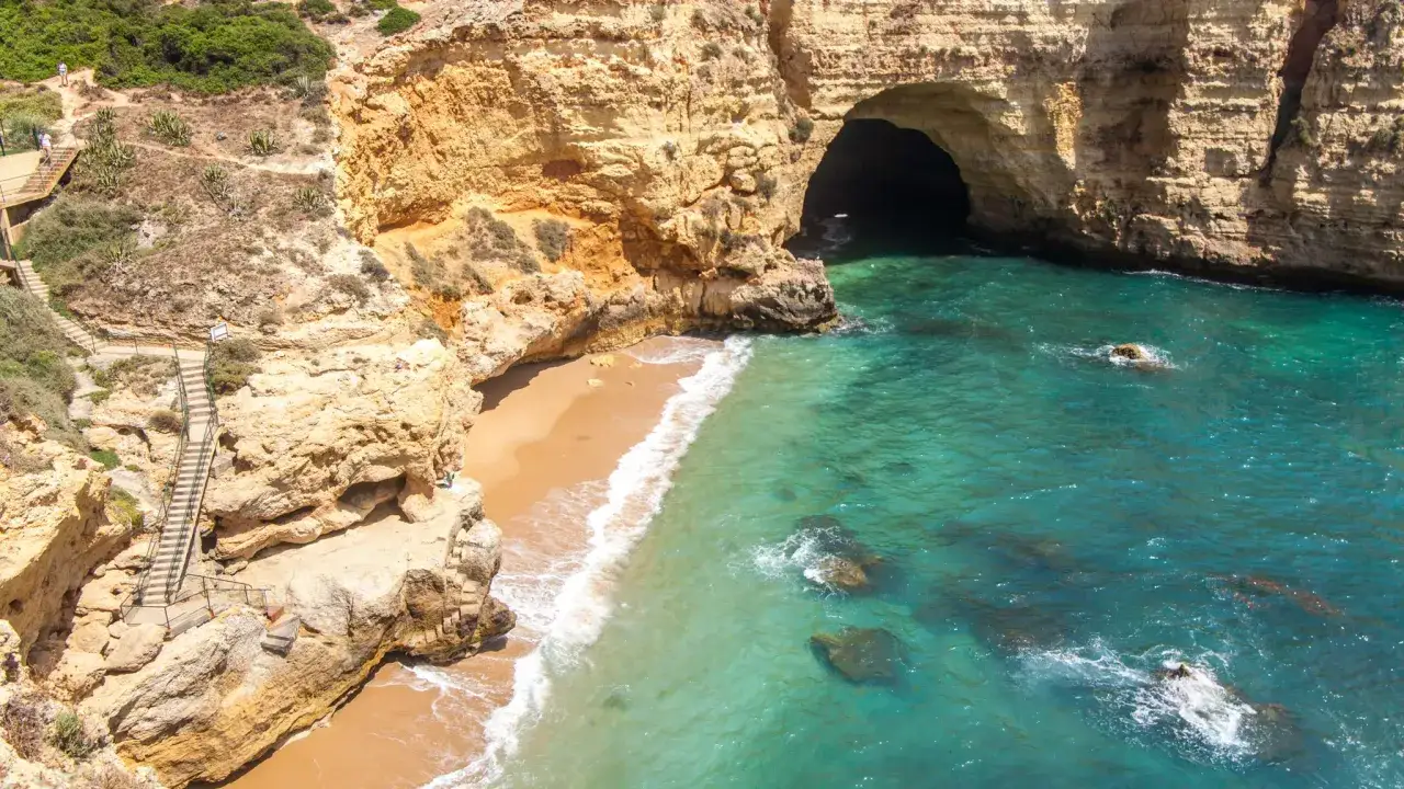 Traumhafte Küste mit Höhle und Treppen – tolle faro urlaub tipps für deine Reise. Türkises Wasser lädt zum Schwimmen ein.
