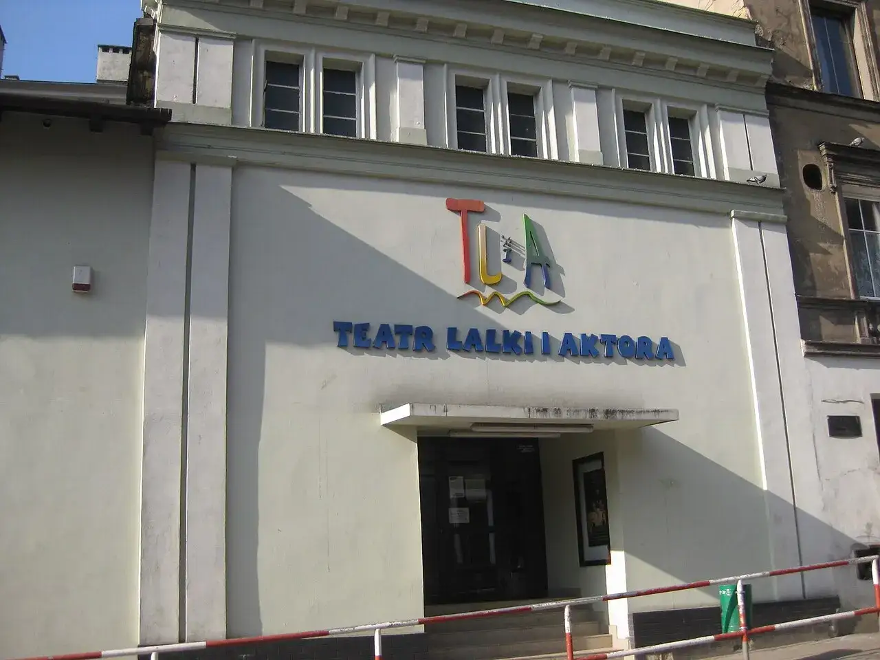 Teatr Lalki i Aktora w Wałbrzychu zaprasza na magiczne przedstawienia. Kolorowe logo i nazwa teatru zdobią fasadę budynku.