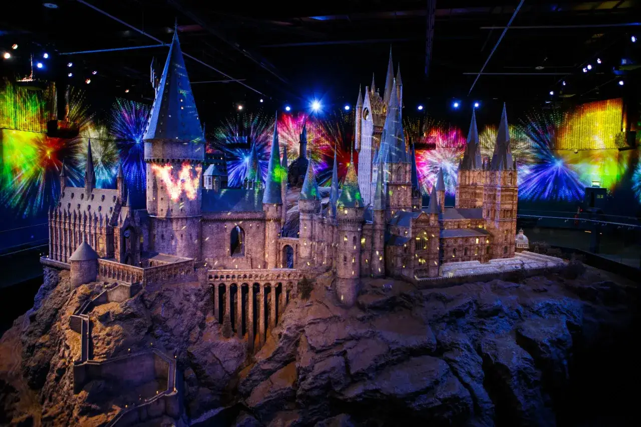 Model zamku Hogwart w muzeum Harry'ego Pottera, oświetlony magicznymi projekcjami fajerwerków.