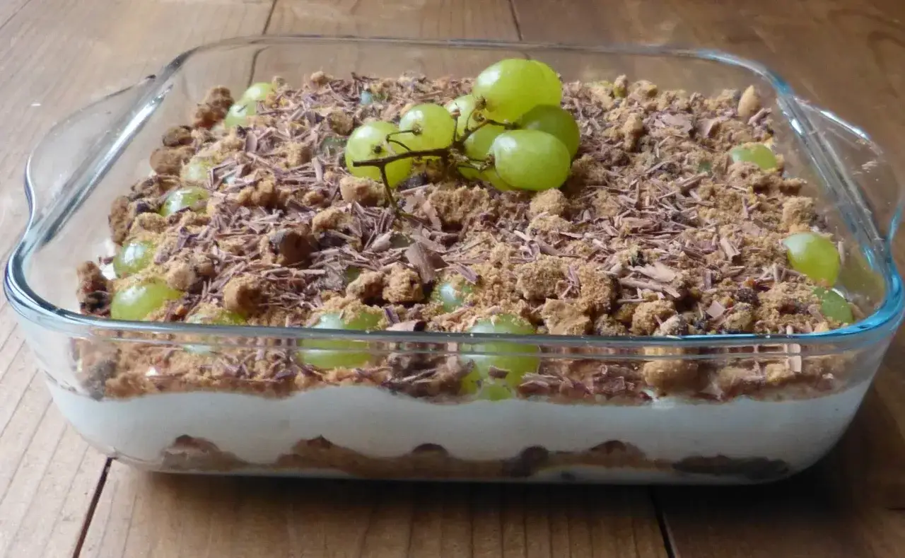 Schichtdessert mit grünen Trauben, Keksbröseln und Schokostreuseln. Ein köstliches Trauben-Cookie-Dessert in einer Glasform.