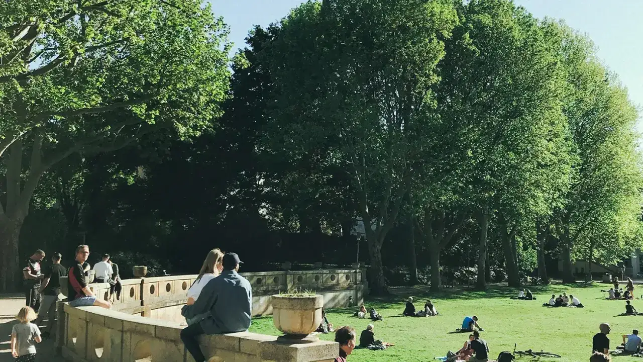 Menschen entspannen sich im Schatten gro&szlig;er B&auml;ume im Rudolph Wilde Park.