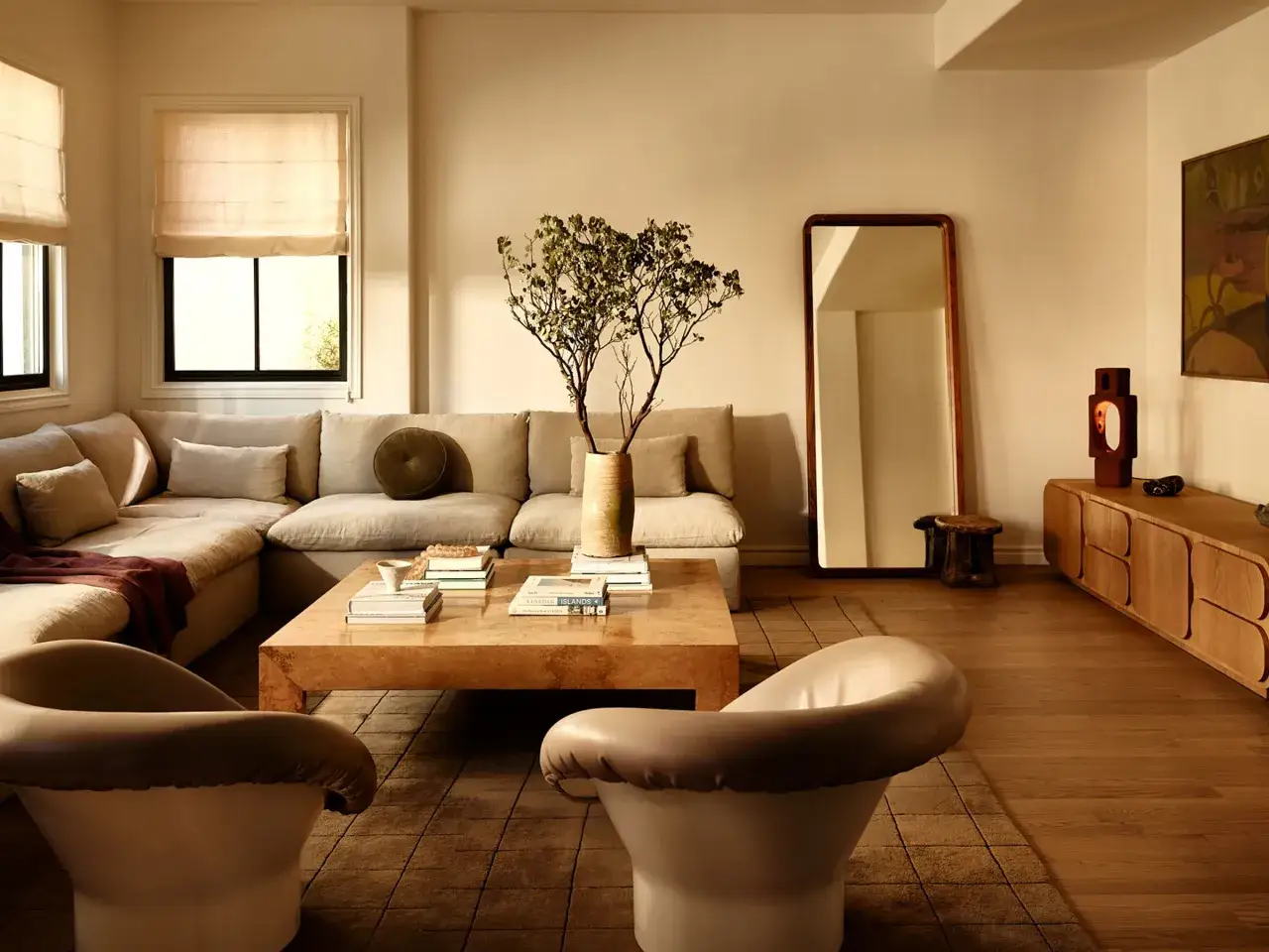 Elegante sal&oacute;n con sof&aacute; modular beige, mesa de centro de madera y dos sillones blancos. Las combinaciones con beige crean un ambiente c&aacute;lido y acogedor.