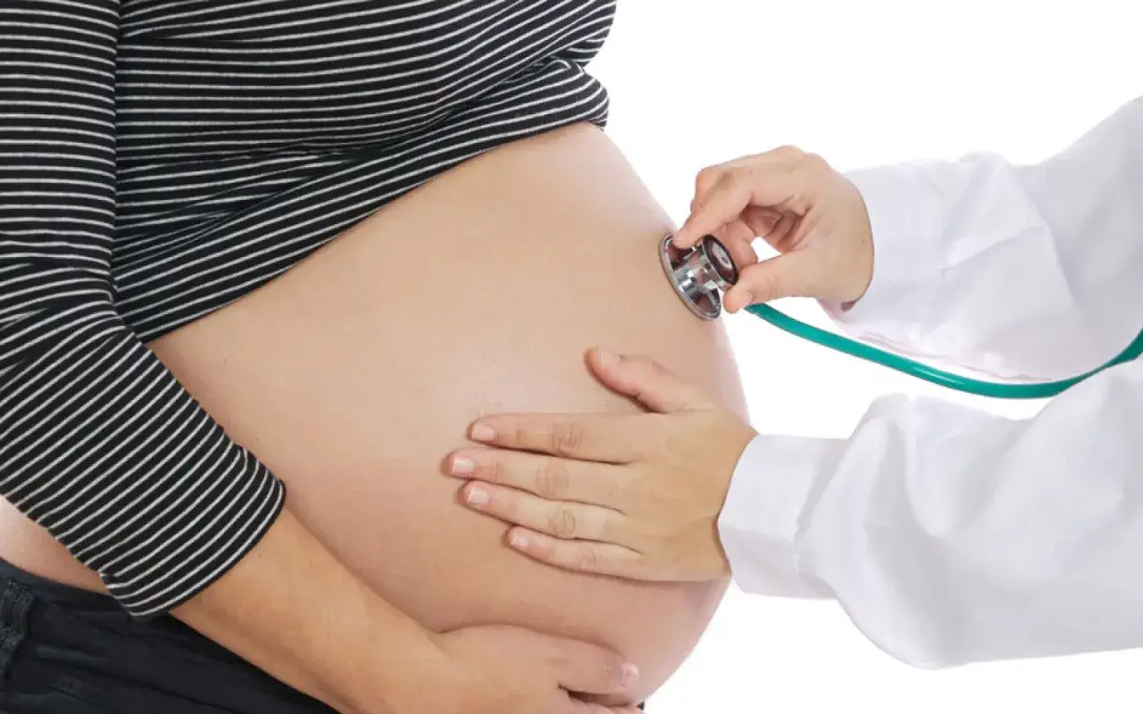 Une sage-femme utilise un st&eacute;thoscope pour le monitoring d'une femme enceinte.