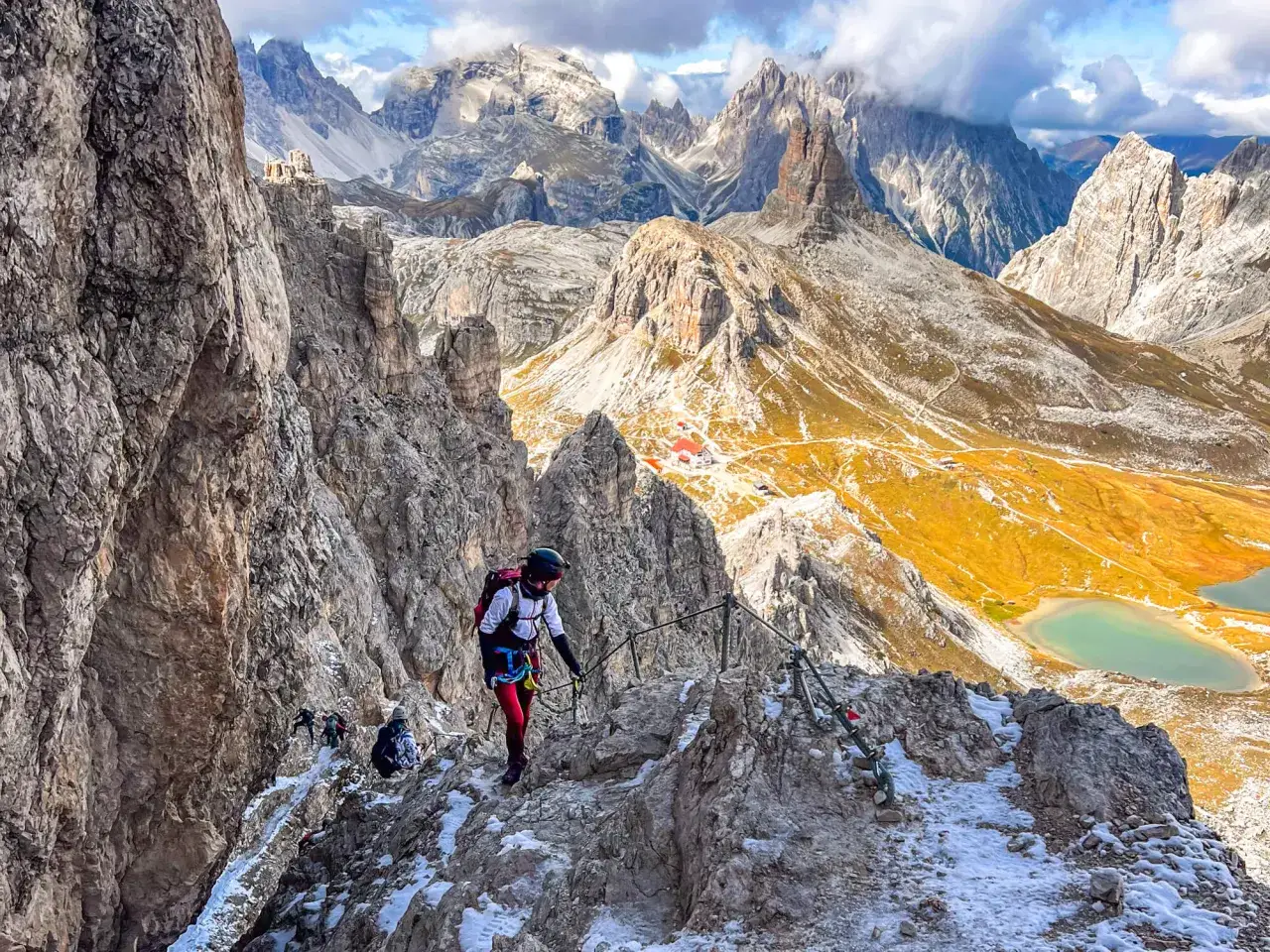 Bergsteiger auf dem Paternkofel Klettersteig in den Dolomiten. Die Route führt über felsiges Gelände mit Drahtseilen gesichert, mit Blick auf malerische Bergseen.