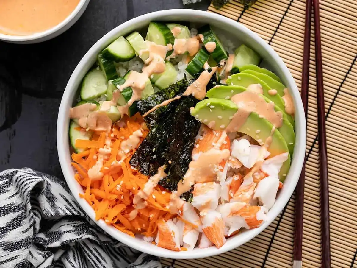 Pyszny poke bowl z ryżem, awokado, krabem, ogórkiem, marchewką i nori. Sos jest pyszny, a porcja ryżu idealna.
