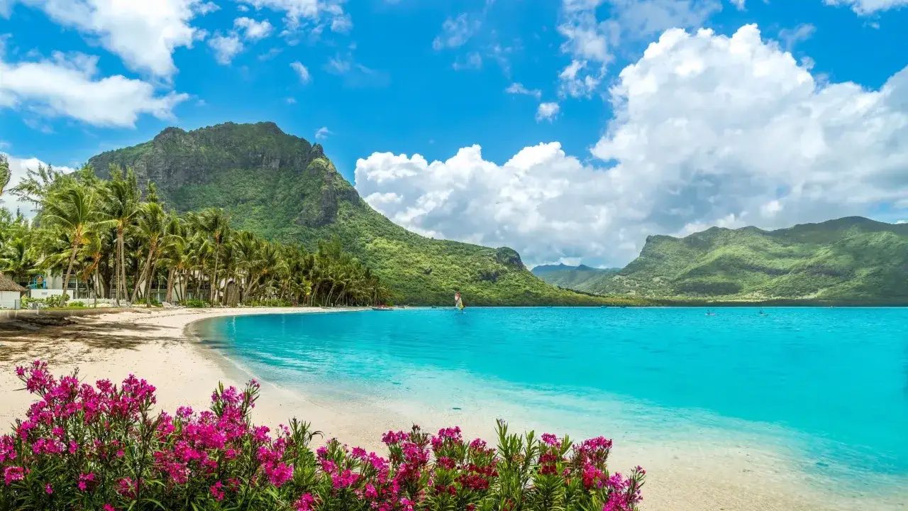 Mauritius pogoda czerwiec: rajska plaża z palmami, turkusowa woda i góry. Idealna pogoda na relaks.