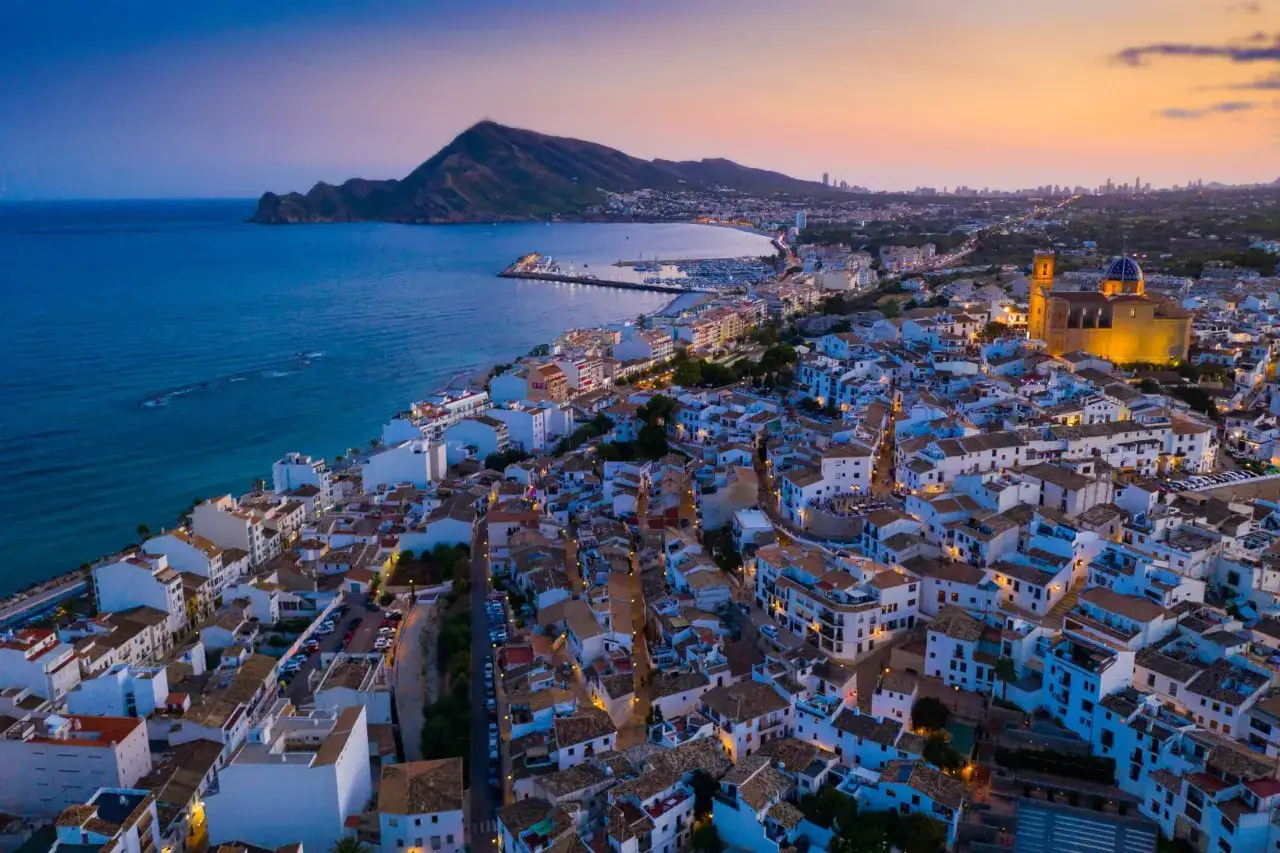 Widok z lotu ptaka na białe miasteczko z niebieską kopułą kościoła, port i góry. To wspaniałe costa blanca atrakcje.