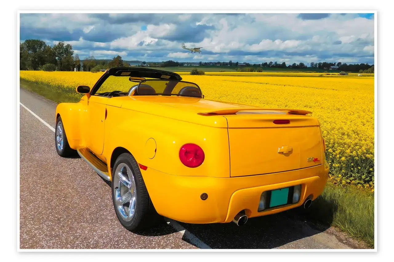 Żółty Chevrolet SSR z otwartym dachem jedzie przez pole rzepaku. Nad nim leci mały samolot.