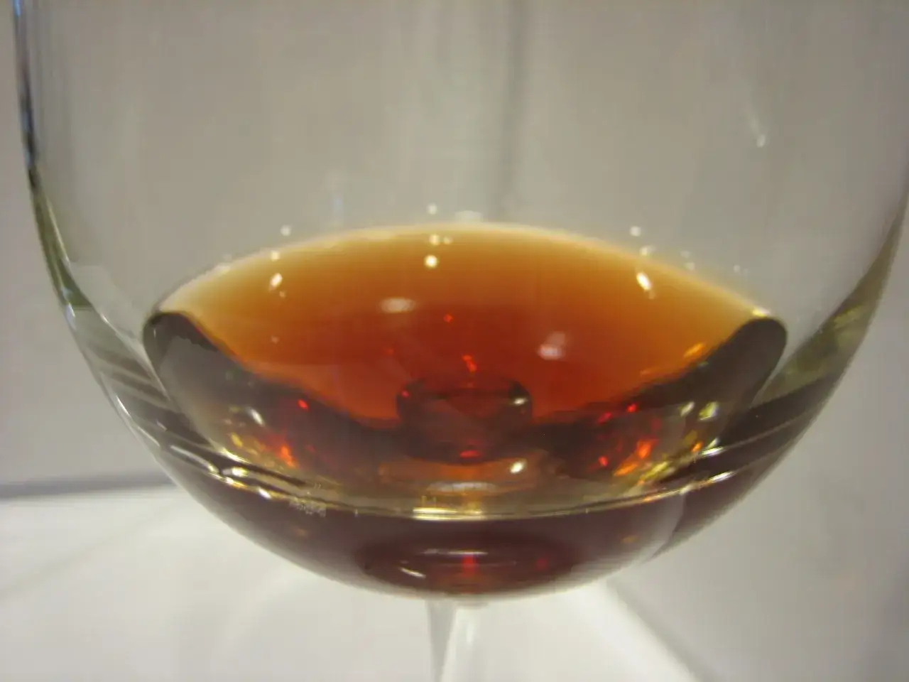 Goutte de vin tourné dans un verre, reflets ambrés et lumineux.