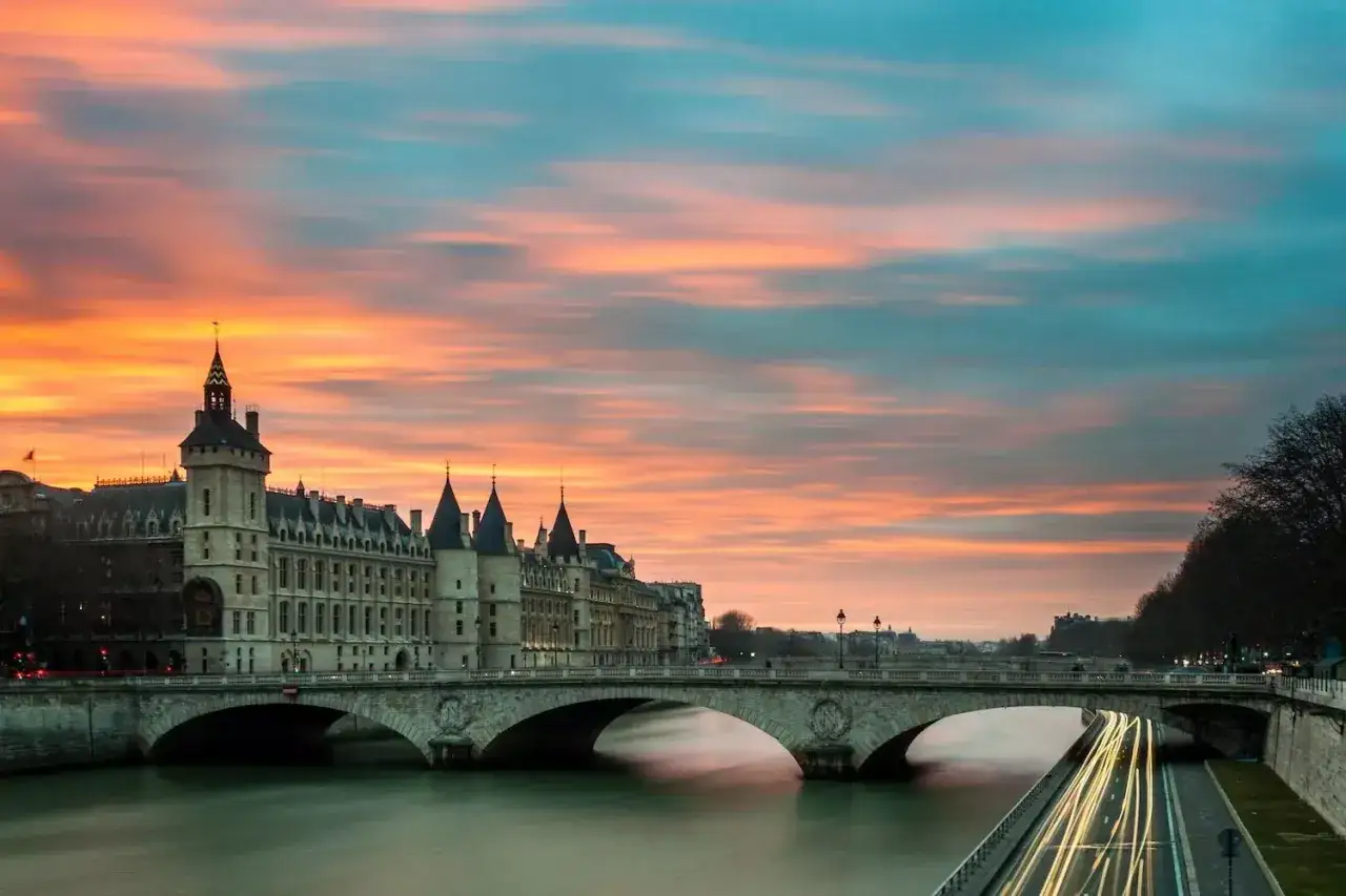 Zachód słońca nad Sekwaną, zamek Conciergerie i most Pont Neuf. Czy Paryż jest bezpieczny? Miasto tętni życiem, nawet o zmierzchu.