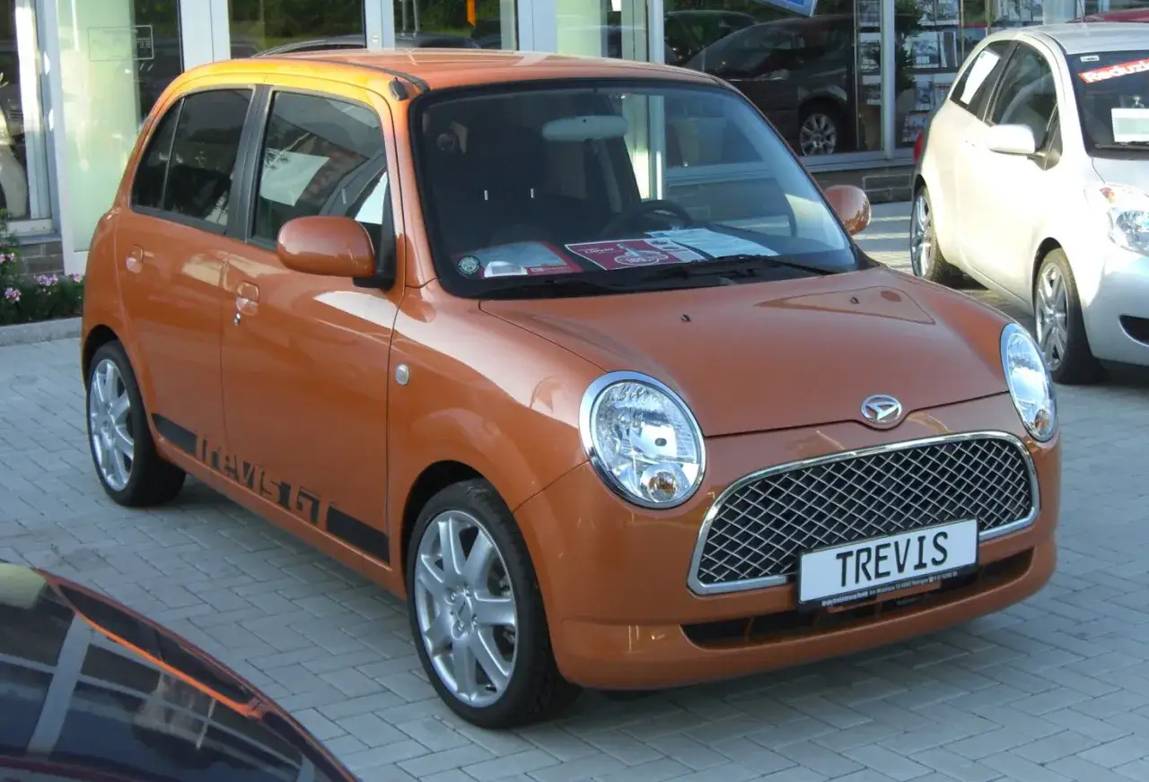Pomarańczowy Daihatsu Trevis GT stoi na chodniku.