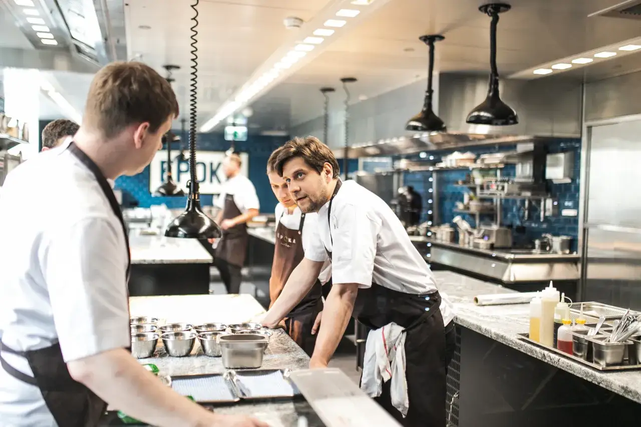 Kucharze w kuchni restauracyjnej, przygotowujący się do pracy. Czy to właśnie tutaj kryje się odpowiedź, dlaczego znany kucharz zamknął wszystkie swoje restauracje z dnia na dzień?