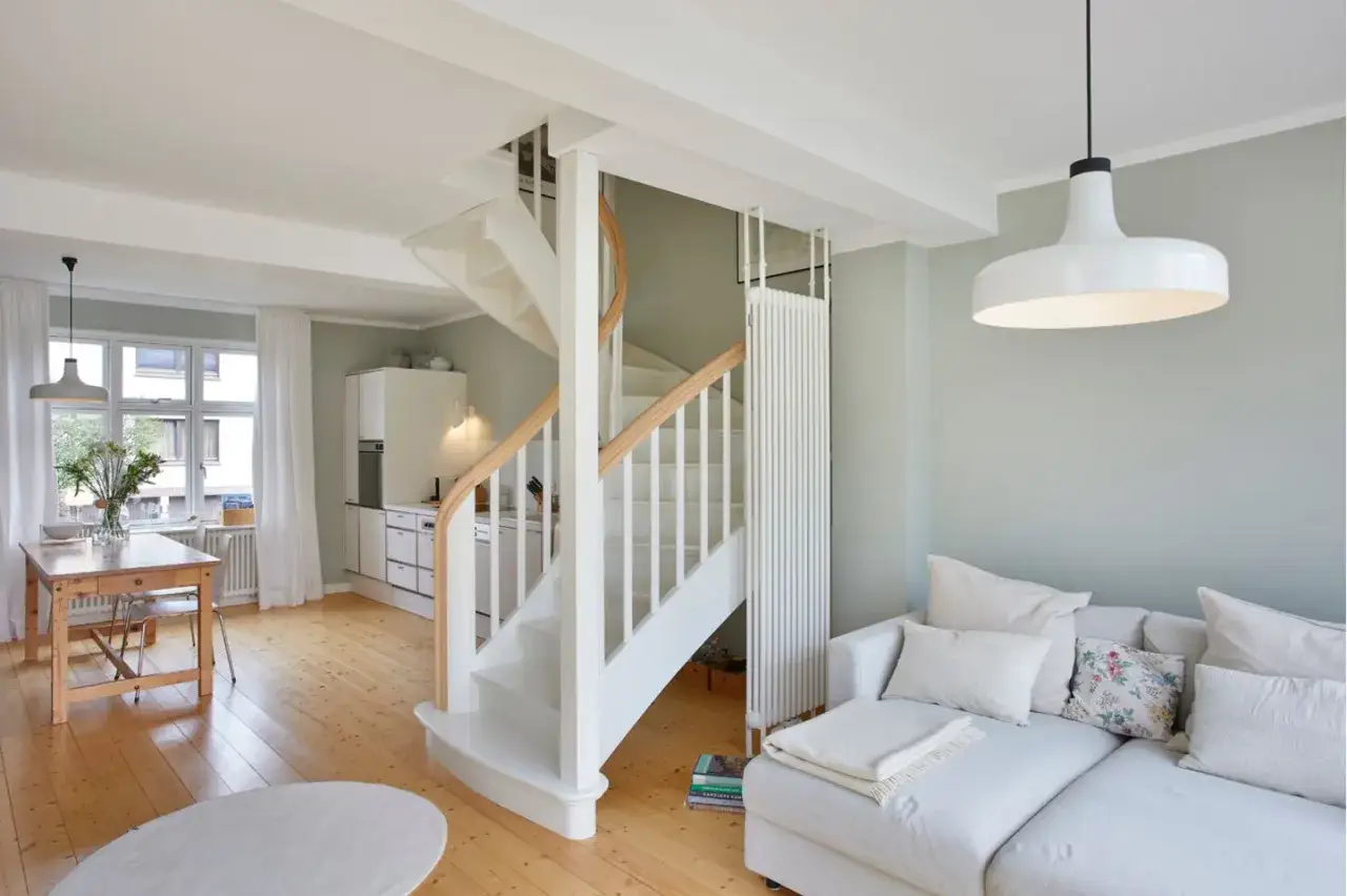 Helles Wohnzimmer mit Essbereich und Küche, ideal für ein schmales Reihenhaus einrichten. Eine weiße Wendeltreppe dominiert den Raum.