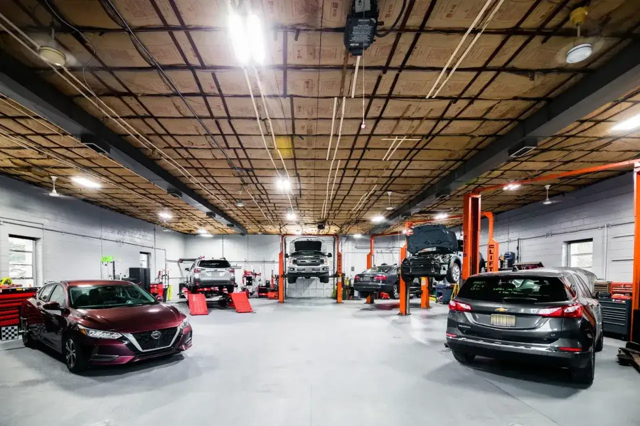 Plano de un taller mecánico con varios coches en elevadores, listo para reparaciones.