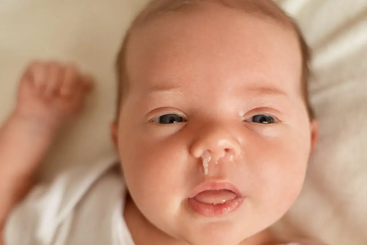Malutkie niemowlę z katarkiem, któremu mama założyła ciepłą **sapka u niemowlaka**.