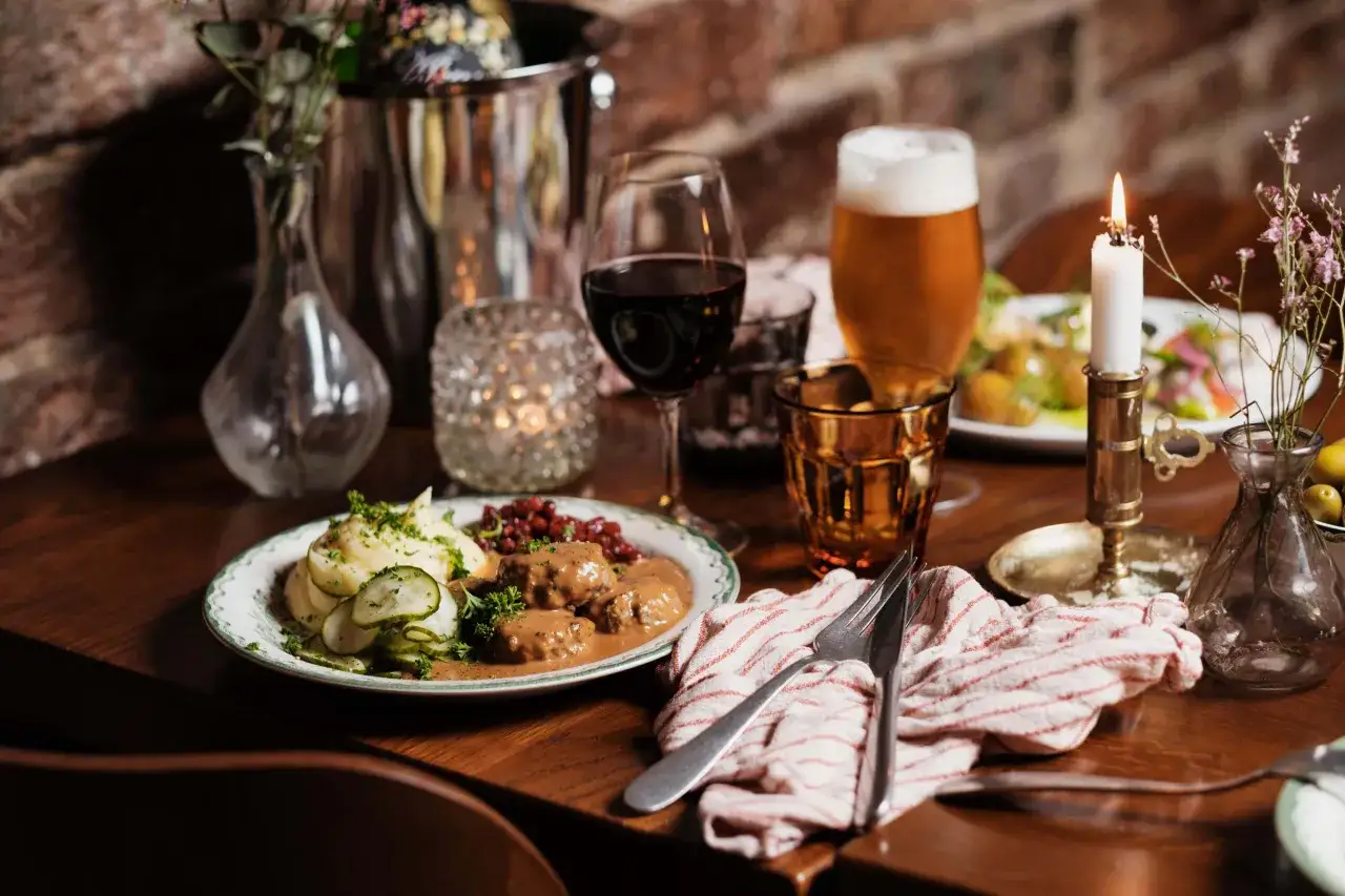 En tallrik med köttbullar, potatismos och lingon. En öl och ett glas rödvin på bordet. Klassisk husmanskost Stockholm.