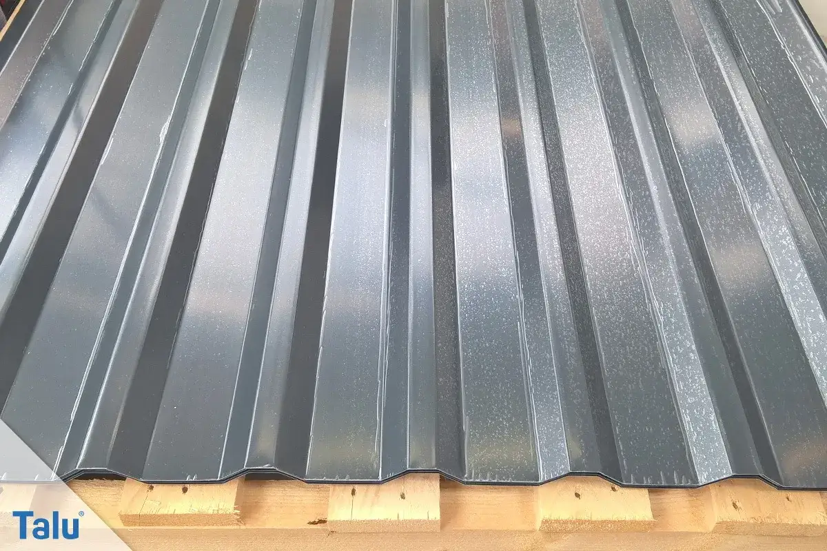 Graue Trapezblechplatten auf Holzpaletten. Informieren Sie sich &uuml;ber die **Blechdach Kosten** f&uuml;r Ihr Bauprojekt.