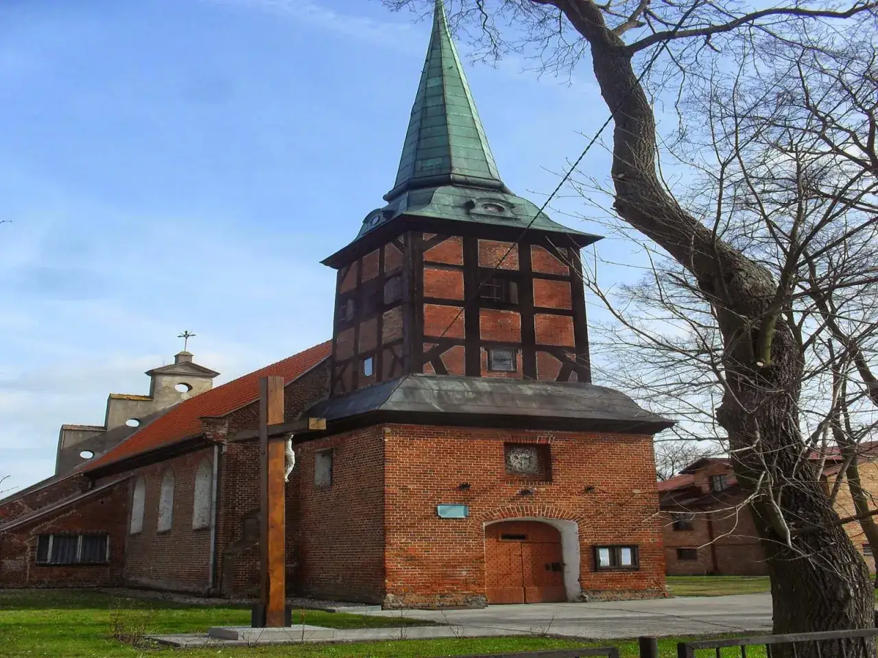 Kościół z wieżą szachulcową, jeden z urokliwych żuław wiślanych atrakcji. Drewniany krzyż przed wejściem.