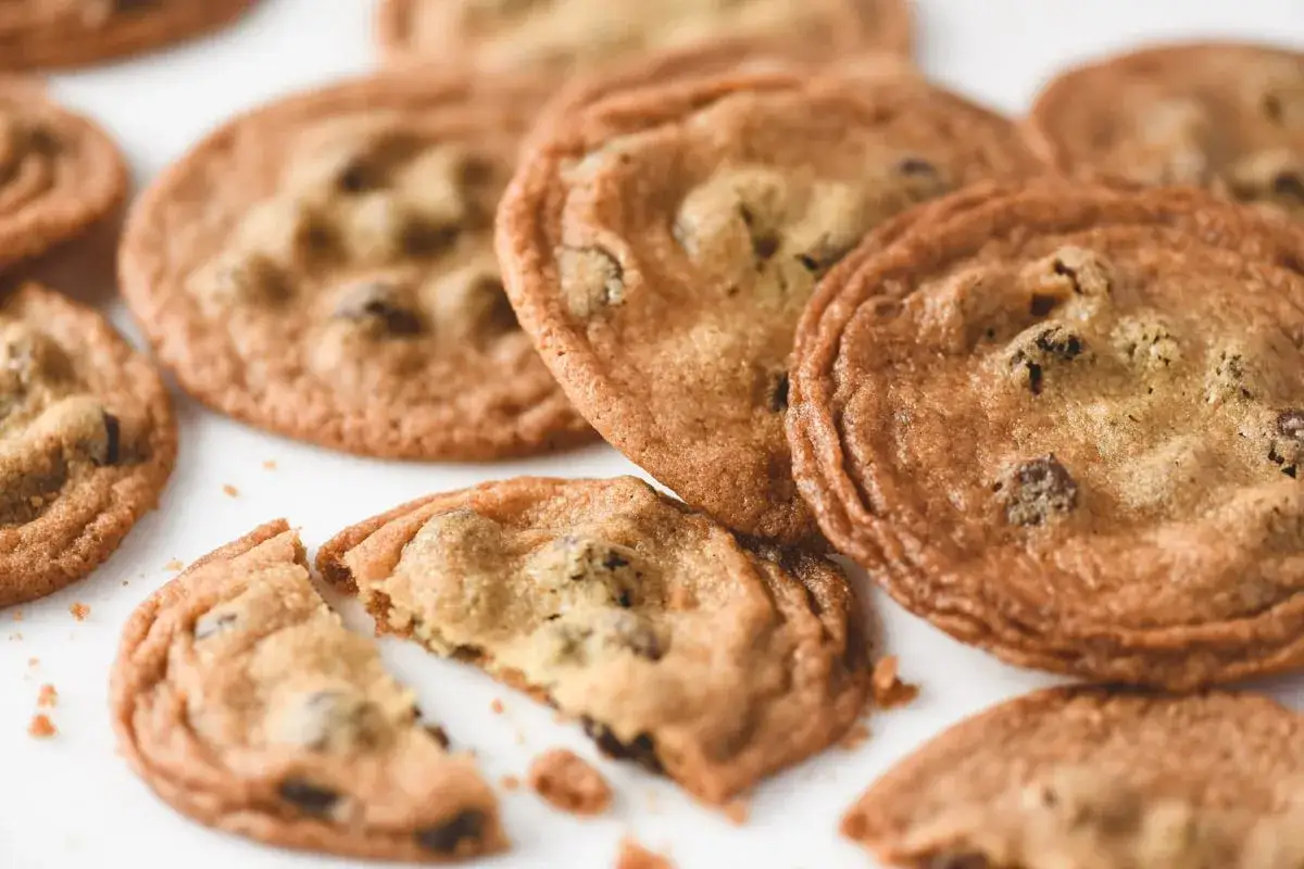 Des cookies aux pépites de chocolat, parfaits pour une recette cookie croustillant. Un est cassé, révélant son cœur moelleux.
