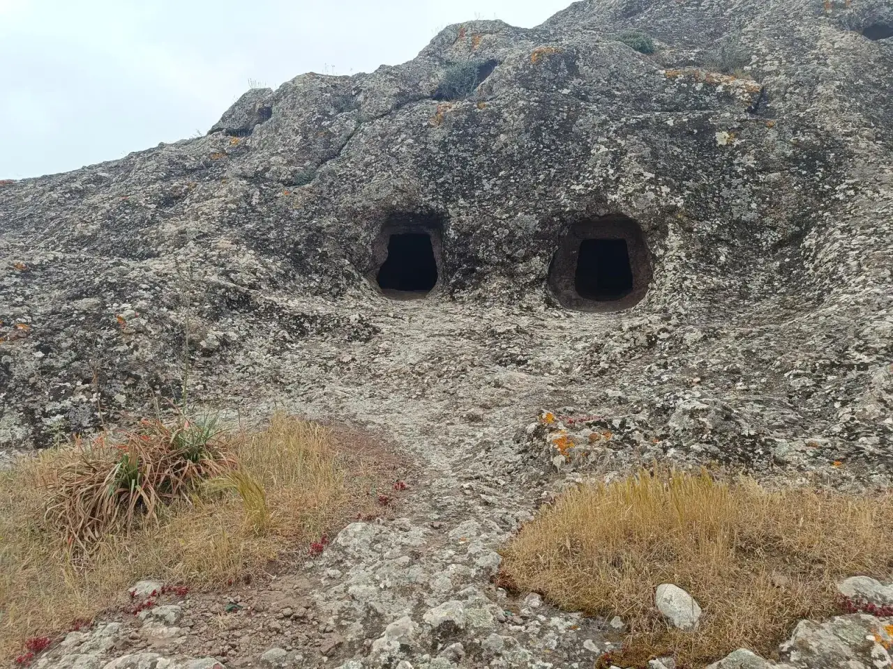 Due grotte scavate nella roccia sul monte Zara, sembrano occhi che osservano il paesaggio arido e roccioso.