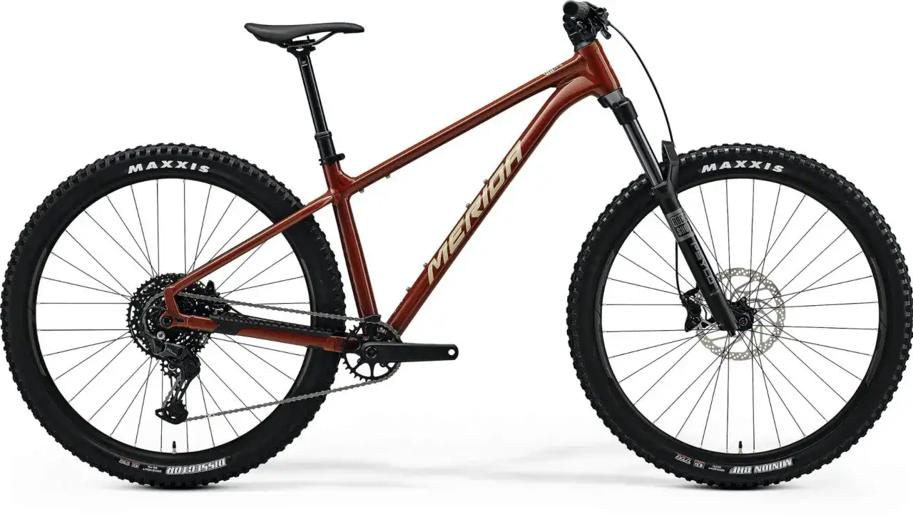 Brązowy rower trailowy Merida z szerokimi oponami Maxxis, gotowy na każdą trasę.