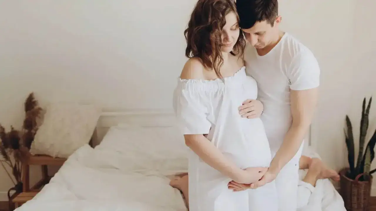 Un couple s'enlacent tendrement, la femme enceinte caresse son ventre. Ils semblent surmonter un blocage psychologique grossesse, trouvant du réconfort l'un dans l'autre.